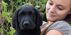 Pepsi, labrador noir chiot dans les bras de sa famille d'accueil